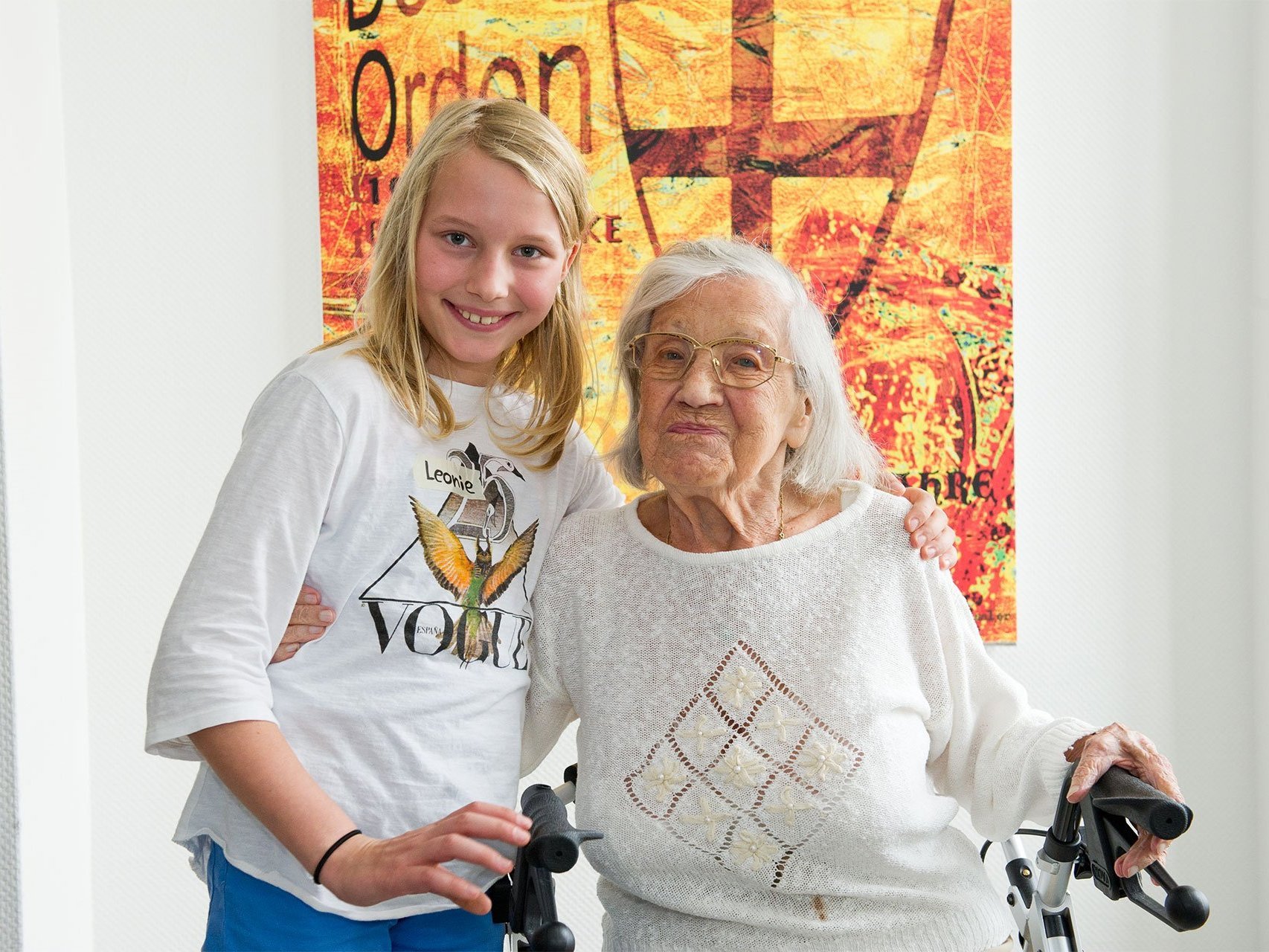 Besuch: In junges Mädchen steht neben einer Frau im Rollstuhl - halten sich gegenseitig im Arm